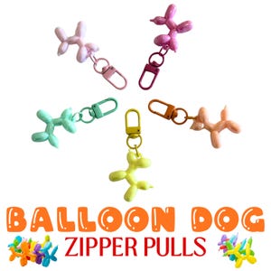 Pode incluir: Uma coleção de puxadores de zíper de cachorro balão coloridos em rosa, roxo, verde, amarelo e pêssego. Cada pingente de cachorro é preso a um fecho de metal. O texto "BALLOON DOG ZIPPER PULLS" é exibido em letras laranja.