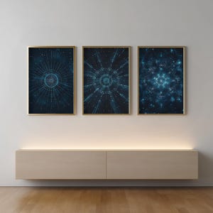 May include: Three framed abstract art prints. Each print features a dark blue and teal design with a gold frame. The artwork has a geometric, radial pattern, resembling a celestial or digital network. The prints are displayed above a light-colored cabinet.