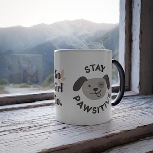 Puede incluir: Taza de cerámica blanca con asa negra que presenta un perro de dibujos animados con las palabras "STAY PAWSITIVE". La taza también tiene las palabras "Go Girl Go" y un diseño floral. La taza está sobre una superficie de madera.