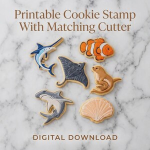 May include: Cookies in the shape of sea creatures, including a shark, stingray, clownfish, and seal, are arranged on a marble surface. The text "Printable Cookie Stamp With Matching Cutter" and "DIGITAL DOWNLOAD" are displayed.