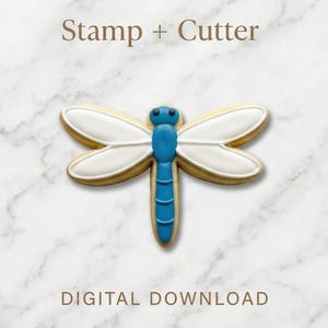 May include: A dragonfly-shaped cookie cutter and stamp. The cookie is decorated with white icing on the wings and a blue body. The text "Stamp + Cutter" and "DIGITAL DOWNLOAD" are displayed on a marble background.