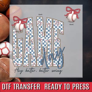 May include: A gray graphic with the words "GAME DAY" in blue and a baseball-themed pattern. The text "Hey batter, batter swing" is below. Two baseballs with red bows are shown. The words "DTF TRANSFER READY TO PRESS" are at the bottom.