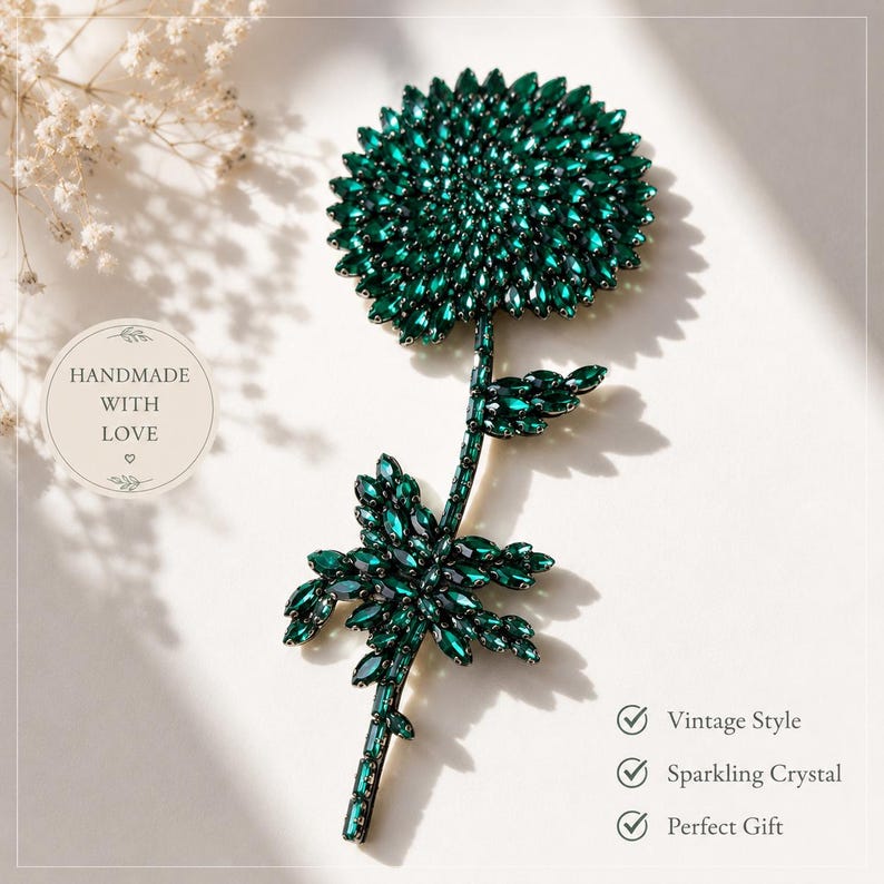 Puede incluir: Un broche con forma de flor cubierto de cristales de color verde oscuro. El dise&ntilde;o presenta una flor grande, circular y de varias capas en la parte superior, un tallo delgado y dos conjuntos de hojas. El texto en la imagen dice: HANDMADE WITH LOVE, Vintage Style, Sparkling Crystal, Perfect Gift.