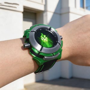Puede incluir: Un reloj de pulsera verde y plateado con una correa negra. La esfera del reloj muestra una figura verde. El reloj está en una muñeca.