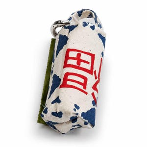 May include: A white and blue patterned bag with a silver clasp and a green accent. The bag has red Japanese characters printed on it. The bag is designed to hold waste bags.