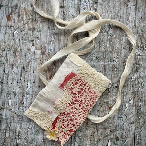 SMALL HAND STITCHED NECKLACE
Beautifully hand stitched pouch to hold your precious memories, a photograph or crystals. Made by slow stitching vintage French linens, lace, silk and quilting fabrics in shades of cream and white, lined with a pretty pink vintage paisley cotton, embellished with small silver bugle beads and a vintage fabric flower. 
It has a simple fold over top with a raw edged cream sari silk ribbon to wear around the neck.
Pouch: 3+1/4" / 8 cm square.
Ribbon drop: 16+1/2" / 42 cm