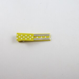 May include: A yellow hair clip with white polka dots and two silver metal bars.