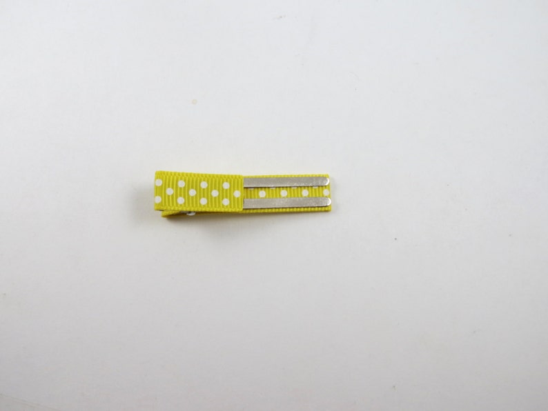 May include: A yellow hair clip with white polka dots and two silver metal bars.
