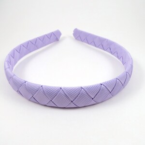 May include: A lavender braided headband for hair. The headband is made of a woven ribbon.