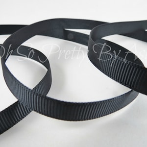 May include: Black grosgrain ribbon, a type of ribbon with a textured, woven surface. The ribbon is shown in a close-up image, with multiple loops of the ribbon.