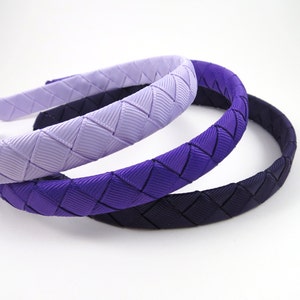 May include: Three woven headbands in shades of purple, from light lavender to dark purple.
