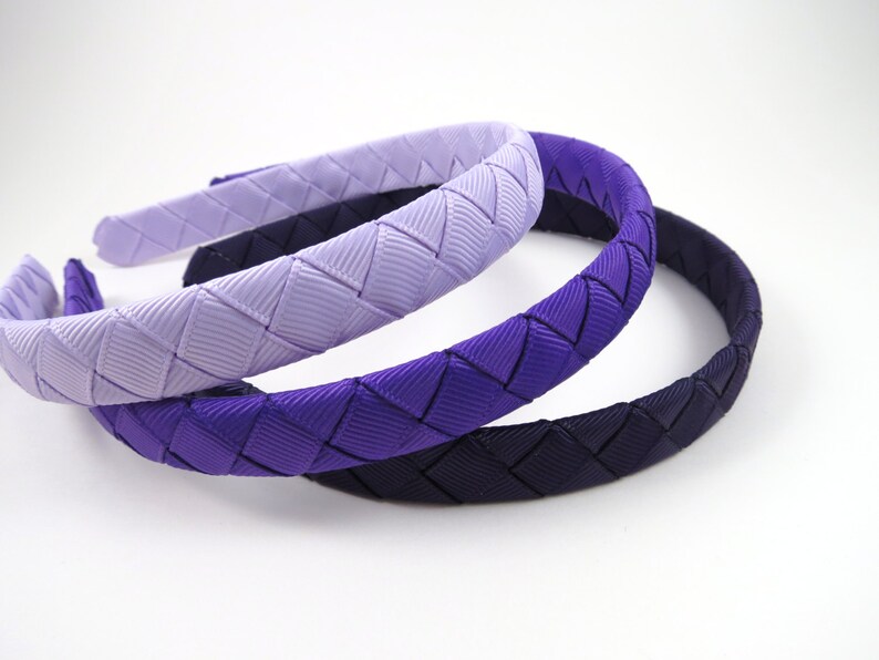 May include: Three woven headbands in shades of purple, from light lavender to dark purple.