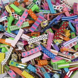 May include: A large assortment of colorful hair clips with various patterns, including polka dots, stripes, and gingham. The clips are made of metal and have a variety of ribbon colors, including pink, blue, green, yellow, and red.