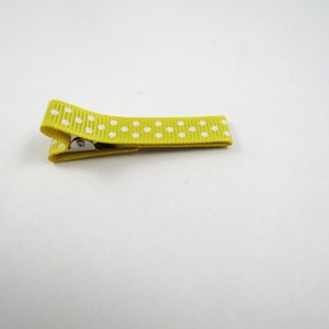 May include: A yellow hair clip with white polka dots.