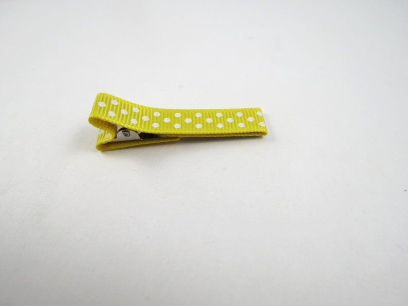 May include: A yellow hair clip with white polka dots.