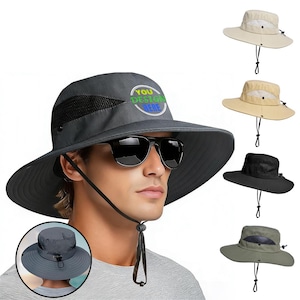 Peut inclure: Un chapeau de soleil gris avec un large bord et une ventilation en maille, avec le texte "YOU DESIGN HERE". D'autres chapeaux beiges, noirs et vert olive sont également présentés. Chaque chapeau a une mentonnière réglable.