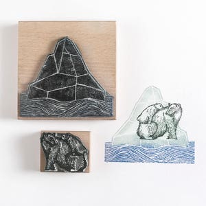 May include: Three wood mounted rubber stamps featuring polar bears and an iceberg. The first stamp shows a black and white iceberg with wavy lines representing water. The second stamp shows two polar bears, one standing and the other sitting on top of the iceberg. The third stamp shows a close-up of the two polar bears.