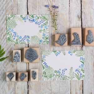 May include: A set of nine wood mounted rubber stamps featuring floral and fern designs. The stamps are arranged on a light wood background with two printed cards featuring the same floral and fern designs.