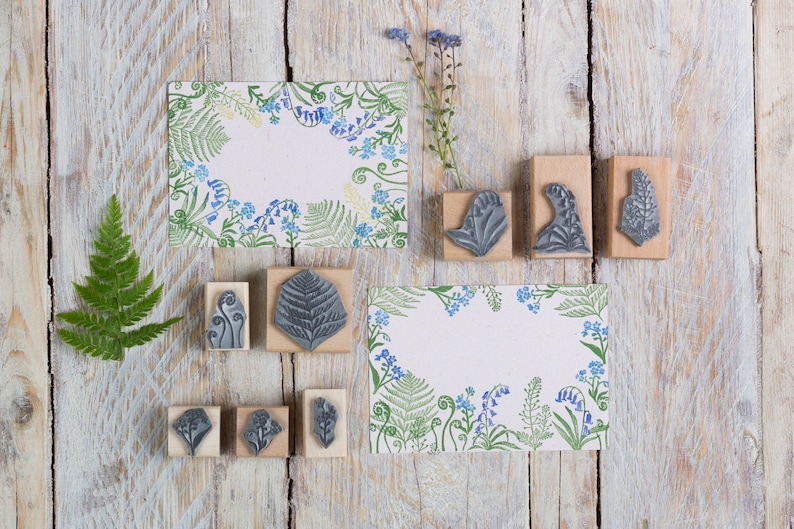 May include: A set of nine wood mounted rubber stamps featuring floral and fern designs. The stamps are arranged on a light wood background with two printed cards featuring the same floral and fern designs.