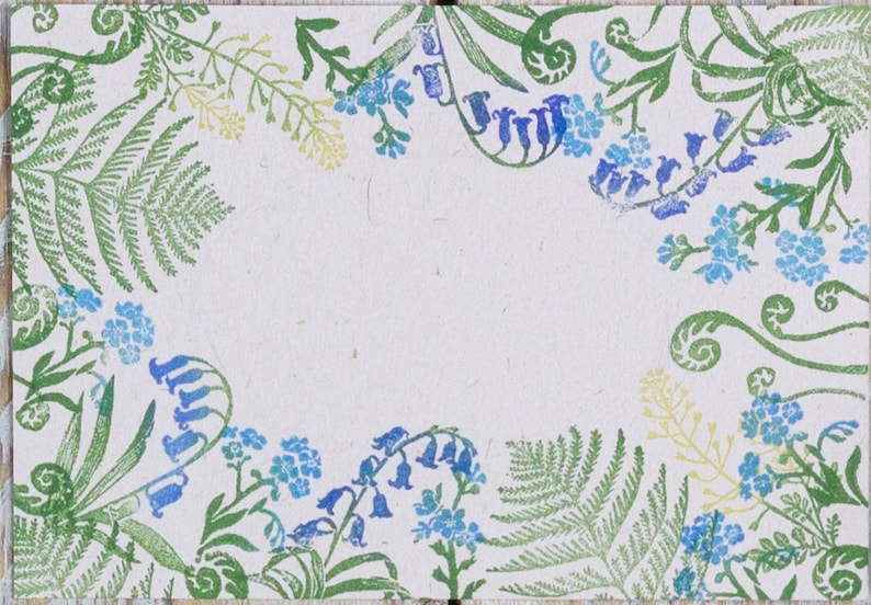 May include: A white background with a green and blue floral border. The border is made up of ferns, leaves, and flowers. The flowers are blue and white.