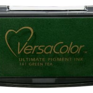 May include: A green ink pad with the text "VersaColor" and "Ultimate Pigment Ink 181 Green Tea" on the front.