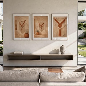 Op de afbeelding: Drie ingelijste wandkunstwerken op een rij, elk met een macramé wandhanger in crème- en terracottatinten. De prints tonen interieurscènes met boogdeuren, potplanten en zachte, warme verlichting.