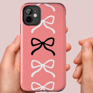 Custodia resistente per telefono Jackie Core con fiocchi Coquette bianchi e neri su sfondo rosa salmone per iPhone 16, 15, 14, 13, 12, 11, 8, 7, Samsung Galaxy S24, S23, S22, S21
