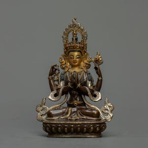 May include: A bronze statue of a deity with multiple arms, featuring gold detailing and intricate designs. The figure is seated in a meditative posture, wearing a crown and jewellery. The statue is set against a plain grey background.