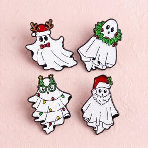 Pode incluir: Quatro pins de esmalte com fantasmas brancos em temas natalinos. Um usa gorro de Papai Noel e chifres de rena, um está envolto em uma guirlanda de azevinho, um usa óculos verdes com luzes coloridas e um tem gorro de Papai Noel e barba branca.
