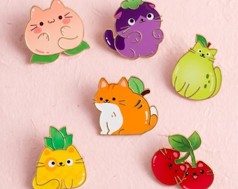 Könnte beinhalten: Ein Set aus sechs Emaille-Anstecknadeln mit katzenartigen Fruchtdesigns. Das Set enthält eine Pfirsich-Katze, eine lila Auberginen-Katze, eine grüne Birnen-Katze, eine orangefarbene getigerte Katze, eine gelbe Ananas-Katze und zwei rote Kirsch-Katzen.