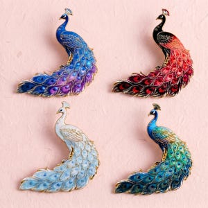 May include: Four peacock-shaped enamel brooches with gold-tone metal outlines. The top left is blue and purple, the top right is black and red, the bottom left is white and light blue, and the bottom right is green and blue with detailed feather patterns.