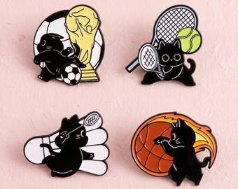 Peut inclure: Quatre broches en émail représentant des chats noirs pratiquant des sports. Un chat joue au football avec un trophée, un autre tient une raquette et une balle de tennis, un troisième est avec un volant de badminton et le quatrième tient un ballon de basket enflammé.