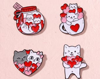 Könnte beinhalten: Vier Emaille-Anstecknadeln mit weißen und grauen Katzen sowie roten und rosa Herzen. Ein Motiv ist ein Glas mit der Aufschrift Full of Love, eines eine Katze in einer Tasse, eines zwei Katzen in Herzform und eines eine Katze mit Herzen.