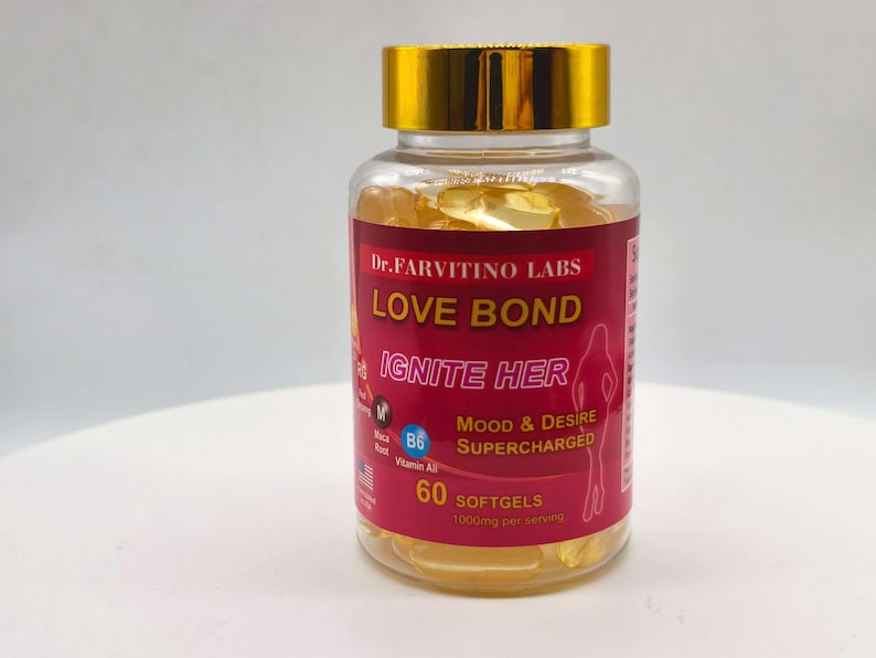 Puede incluir: Una botella transparente con tapa dorada llena de c&aacute;psulas blandas amarillas. La etiqueta roja tiene el texto blanco "LOVE BOND IGNITE HER". La botella contiene 60 c&aacute;psulas blandas y est&aacute; etiquetada como "Mood & Desire Supercharged".