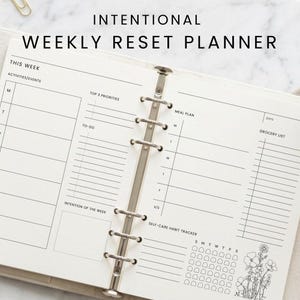 May include: Open weekly planner with the text "INTENTIONAL WEEKLY RESET PLANNER." The planner has sections for activities, priorities, meal plans, and a grocery list. A self-care habit tracker and floral illustration are also included.