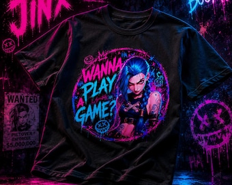 May include: A black short-sleeved t-shirt featuring a circular graphic of a blue-haired character with the text "WANNA PLAY A GAME?" in pink and blue. The design includes graffiti-style elements, including a "JINX" logo and a "WANTED" poster.