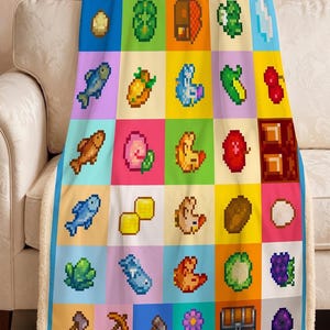 May include: A colourful pixel art blanket with a grid of squares, each showing a different item from a video game. The blanket has a blue border and a soft, white sherpa backing. The items include food, tools, and other game elements.