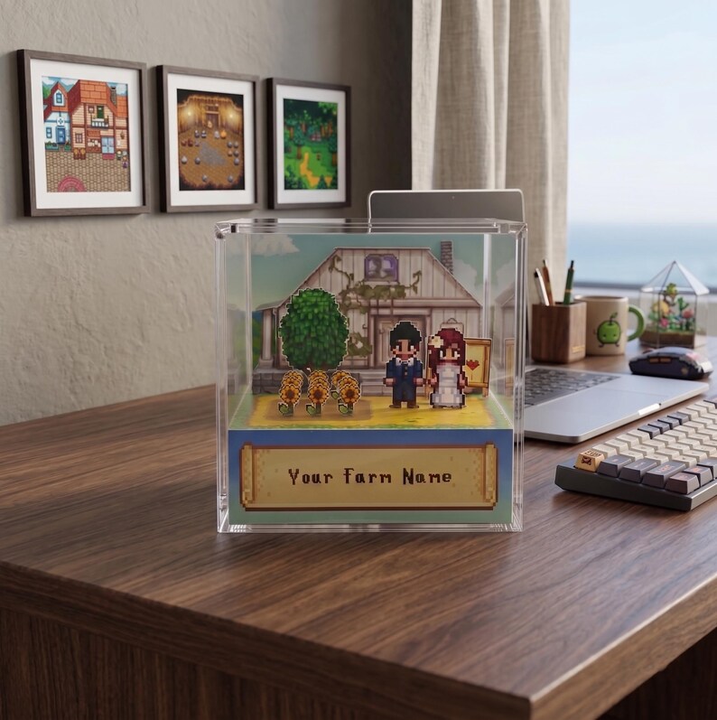 May include: A clear acrylic display case featuring a pixelated farm scene with a house, tree, and couple. The base has a banner that reads "Your Farm Name". Three framed pixel art images hang on the wall behind the case.