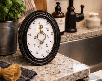 Soporte para anillos ovalado negro con marco, expositor de joyas