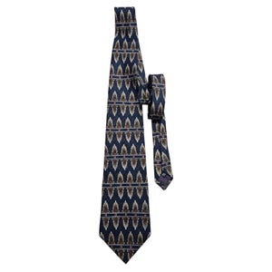 May include: A navy blue tie with a repeating pattern of brown and white leaf-like shapes. The tie is made of a smooth fabric and has a classic pointed end. The tie is a formal accessory.