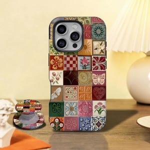 May include: A smartphone case with a mosaic tile design in various colours, including floral, geometric, and butterfly patterns. A matching pop-socket is also visible. The case is designed for a smartphone.