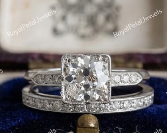 Peut inclure: Une bague de fiançailles argentée avec une pierre centrale carrée bordée de milgrain sur un anneau orné de petites pierres rondes, accompagnée d'une alliance assortie sertie d'une rangée de petites pierres rondes dans un canal.