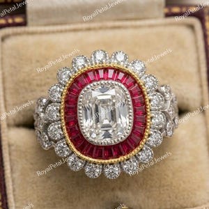 Puede incluir: Un lujoso anillo con una gran piedra central clara de forma rectangular, rodeada por un halo rojo de piedras más pequeñas. El anillo tiene una banda dorada y está incrustado con piedras preciosas claras más pequeñas, creando un efecto deslumbrante.