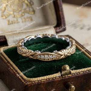 May include: A gold and silver ring featuring a floral pattern and small diamonds. The ring is presented in a vintage-style jewellery box with a green velvet lining. The box is brown with gold detailing and the text "Est. 1879".