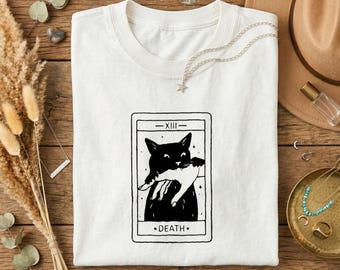 Camiseta informal blanca con estampado gráfico de gato negro sosteniendo una mano blanca y carta del Tarot de la Muerte XIII.