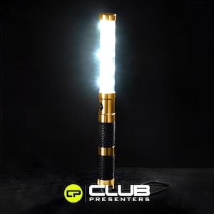 Könnte beinhalten: Ein hell beleuchtetes Präsentationswerkzeug in Gold und Schwarz. Das Gerät hat ein helles weißes Licht, goldene Akzente und einen strukturierten schwarzen Griff. Das Logo "CLUB PRESENTERS" ist unten sichtbar.