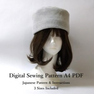 May include: A light gray, rectangular hat with a rounded top is displayed on a mannequin head with brown hair. The text "Digital Sewing Pattern A4 PDF" is below the hat, along with "Japanese Pattern & Instructions" and "3 Sizes Included."
