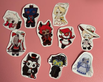 May include: A collection of nine die-cut stickers featuring stylized cartoon characters with button eyes. The characters include various figures in colorful outfits, including red, black, white, and blue designs, each with distinct hair and accessories.
