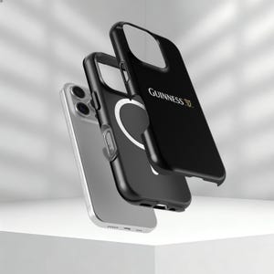 May include: Three black iPhone cases with the Guinness logo and a silver iPhone. The cases are black with a white circular design and the Guinness logo in gold. The phone is silver.