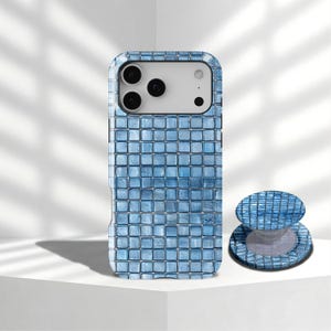 May include: A blue mosaic-patterned phone case and matching phone grip. The case is designed to fit a smartphone, featuring a grid of small, square tiles in varying shades of blue. The phone grip has a similar design and is round.